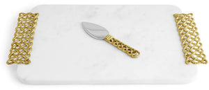 The Michael Aram Love Knot Cheese Board with Spreader is a white marble serving tray featuring gold-patterned handles that symbolize unity, paired with a matching cheese spreader placed at the center.