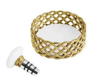 The Michael Aram Love Knot Wine Coaster and Stopper Set features an elegant gold-toned woven design with white accents, symbolizing unity and connection through its intertwined motif.