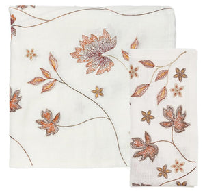 The Kim Seybert Maple Hues Collection features a white cloth napkin and tablecloth set with brown and orange autumnal embroidery—perfect for a fall table setting.