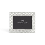 The Michael Aram Love Knot Silver Frame Collection features a decorative silver frame with an intricate lattice design, symbolizing unity, and includes a 5x7 placeholder card.