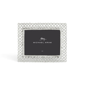 The Michael Aram Love Knot Silver Frame Collection features a decorative silver frame with an intricate lattice design, symbolizing unity, and includes a 5x7 placeholder card.