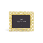 The Michael Aram Love Knot Gold Frame Collection features a gold lattice photo frame with a black card at the center, inspired by the Love Knot motif to symbolize unity and connection.