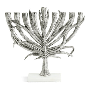 The Michael Aram Silver Palm Menorah, Small features silver branches inspired by palm leaves, set on a white rectangular base, showcasing the detailed artistry of the Palm Collection.