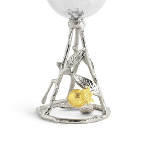 A close-up of Michael Aram's Pomegranate Silver & Gold Kiddish Cup shows a silver stem with leaf and branch details, featuring a small gold pomegranate at the base—a tribute to symbols of abundance.