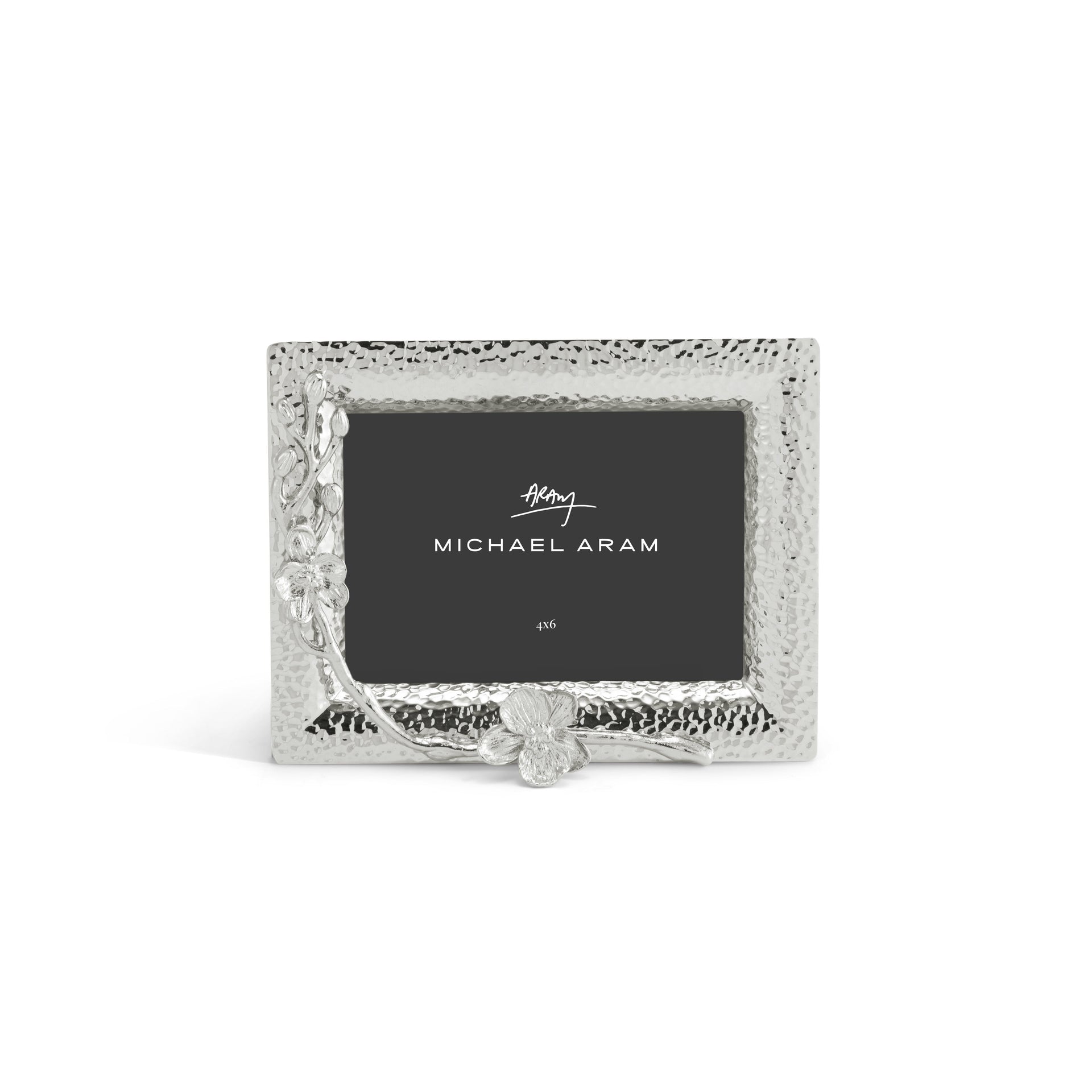 A silver hammered metal photo frame from the Michael Aram White Orchid Frame Collection features floral orchid-inspired accents and includes a "Michael Aram" placeholder card, capturing the purity and elegance of the collection.
