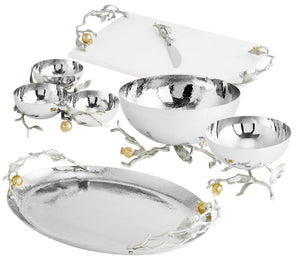 A set from Michael Aram’s Pomegranate Silver & Gold Serveware Collection, featuring silver bowls, a platter, and a cutting board with knife—all adorned with branch and flower accents in stainless steel, nickelplate, and goldplate.