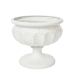 The Juliska Large Whitewashed Decorative Urn features a pedestal design with scalloped patterns and circular accents, making it an elegant centerpiece or a stylish addition to your formal garden décor.