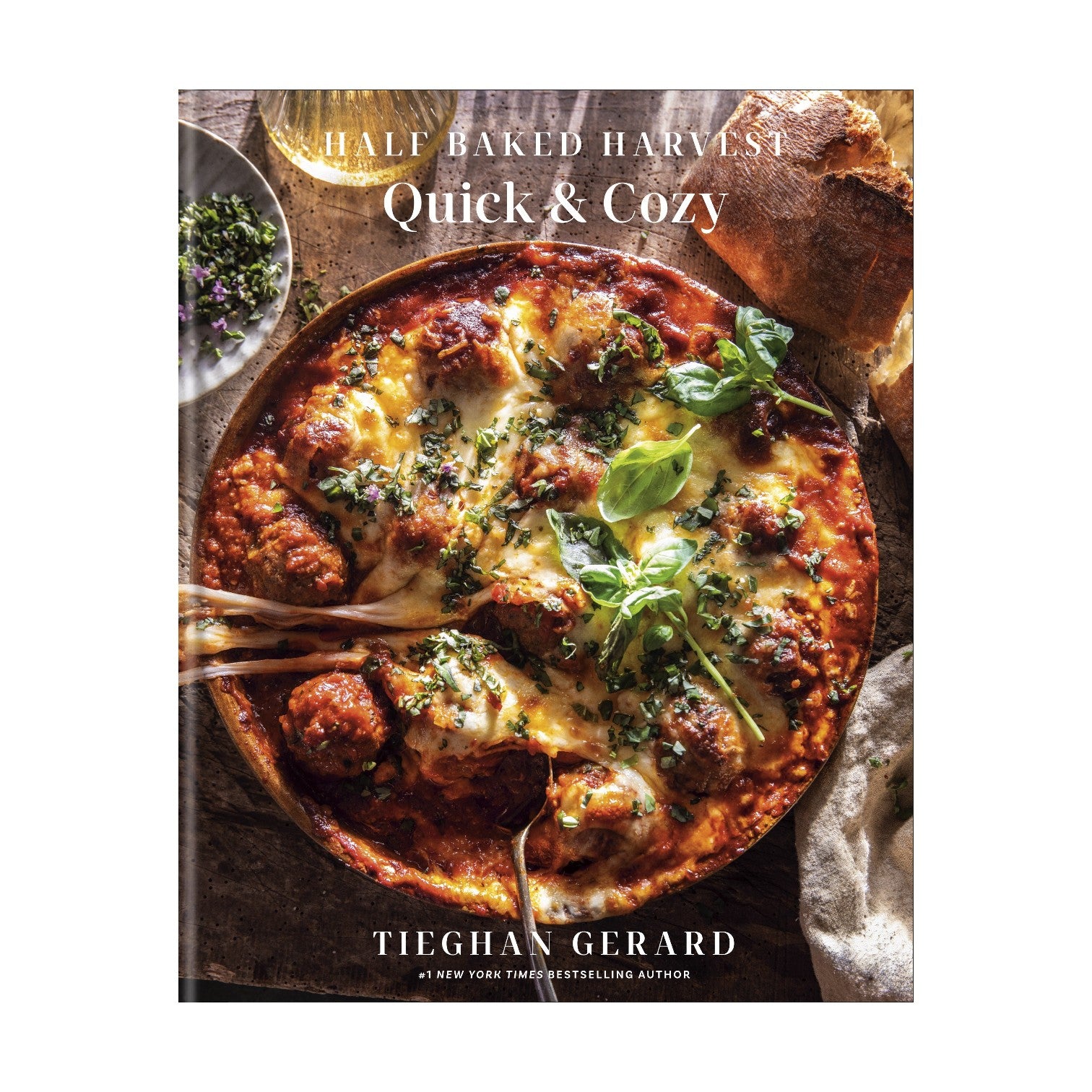 The cover of "Half Baked Harvest Quick & Cozy" by Penguin Random House shows a cheesy baked dish with fresh greens, capturing the cookbook’s collection of quick comfort food recipes ideal for busy weeknights.