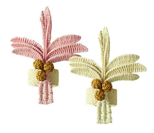 The Duggan Society Palm Napkin Ring comes in sets of two, each handwoven from Iraca Palm with trunks in pink/beige or yellow/beige, finished with three pinecone-like accents at the base.