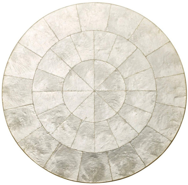 Circular Kim Seybert Capiz placemat in a neutral tone featuring segmented patterns radiating from the center.