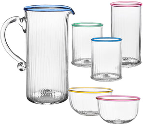 The Nell Drinkware Collection by Juliska features a clear glass pitcher with blue rim and handle, three tall glasses, two short glasses, and two small bowls with colored rims—all mouth-blown in the Czech Republic.