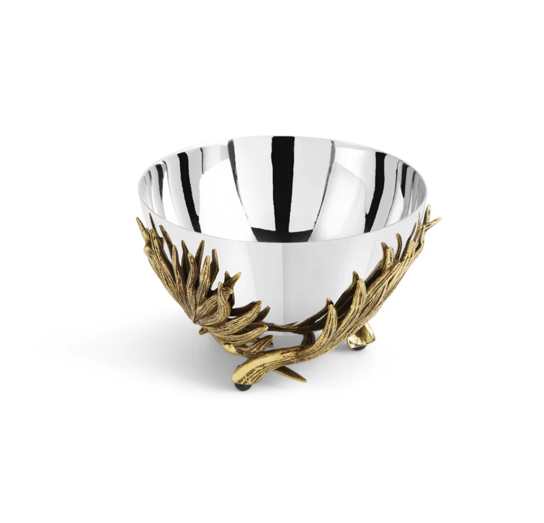 The Michael Aram Palm Nut Dish is a silver metal bowl with sculpted textures and ornate gold-toned branch and leaf designs at the base, shown on a plain white background.