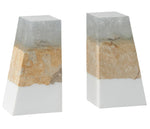 The Made Goods Otis Bookends are geometric, pyramid-shaped sand resin pieces with a layered design in white, tan, and gray, evoking the look of multi-layered colored sand or natural coral stone.