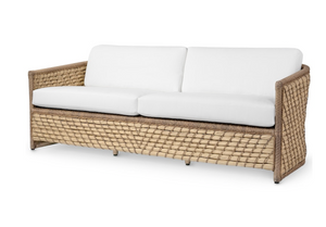 The PALECEK Capitola Outdoor Sofa in Nit Witty Sea Salt features a woven tan synthetic seagrass frame and white cushions, shown on a plain white background—an ideal outdoor furniture addition for any patio or garden.