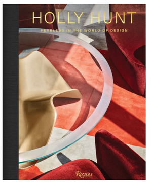 The "Holly Hunt: Fearless In The World of Design" book by Rizzoli features a modern cover with a glass table, abstract gold object, and red velvet chairs on a geometric floor, celebrating bold American design.