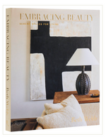 The cover of "Embracing Beauty" by Rizzoli displays a neutral-toned room featuring a lamp, pillow, and abstract wall art.