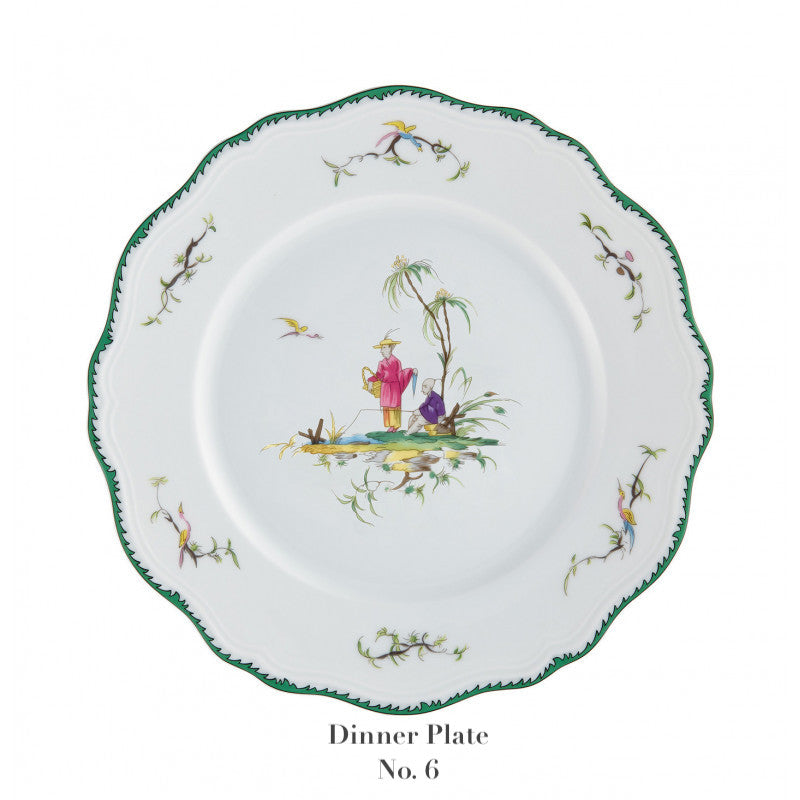 White dinner plate from the Raynaud Longjiang Dinnerware Collection with a scalloped green edge, floral accents, and two figures in traditional attire near trees. Below: "Dinner Plate No. 6". Inspired by Vieux Marseille pastoral scenes.