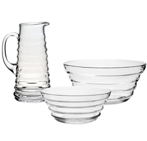 The William Yeoward Crystal Ripples Serveware Collection, featuring a clear glass pitcher and two bowls with horizontal ridges, is displayed on a white background for an artisanal touch.