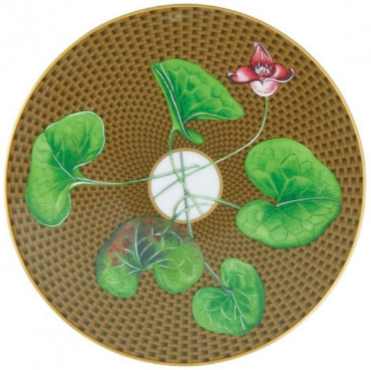 The Tresor Fleuri Marron Dinnerware Collection by Raynaud features hand-painted plates with a brown textured surface, green leaves, and a central pink flower, adding narrative richness to any setting.