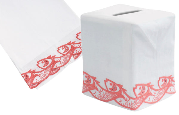 A white Italian linen tissue box cover from Haute Home's Scrollfish Collection, coral, with a hand embroidered red fish pattern along the bottom edge and a matching tissue placed next to it.