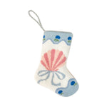 The Let's Shellebrate Needle Point Stocking by Bauble Stockings features a pink seashell, light blue bow, and blue floral border with a white hanging loop—perfect for coastal holiday decor inspired by Palm Beach Lately.