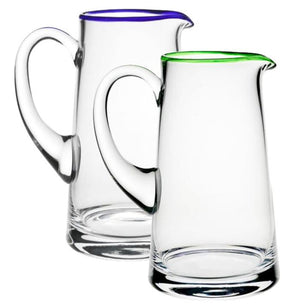 Two clear pitchers from the Siena Pitcher Collection by William Yeoward Crystal, one with a green rim and one with a purple rim, add a pop of color on a white background. Proposition 65 warning may apply.