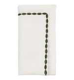 The Swag Napkin Set by Kim Seybert features white linen napkins, each with a neatly folded design and green leaf-patterned embroidered borders on two edges—ideal for elegant table settings.