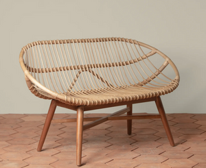 The Emile Rattan Bench by Selamat adds organic charm with its rounded back and wooden legs, set on a terracotta tile floor against a plain beige wall.