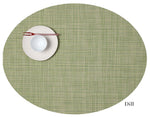 The oval green Chilewich placemat displays a white plate, bowl, and red-brown chopsticks at the top left. "Dill" is on the lower right. Easy to clean with bleach-based cleanser—perfect for any dining occasion.