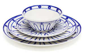 Themis Z’s Kyma Blue Dinnerware Collection, inspired by the Greek Aegean sea, features blue geometric patterns on a bowl stacked atop three plates of varying sizes, evoking tranquil blues.
