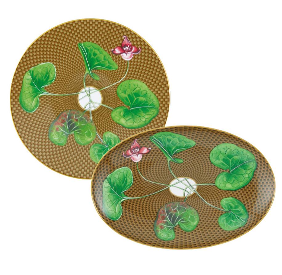 The Tresor Fleuri Marron Dinnerware Collection by Raynaud showcases two hand-painted plates with a brown patterned background, green leaves, and pink flowers radiating from a central white circle, capturing exquisite porcelain artistry.