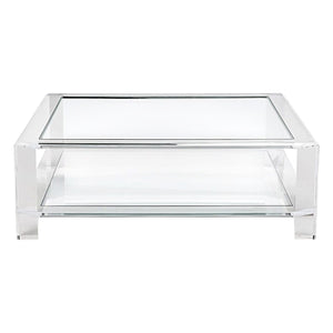 The Surrey Square Acrylic Cocktail Table by Interlude Home features a clear glass top and shelf with a sleek metal frame in chrome, making it ideal for modern coffee table settings.