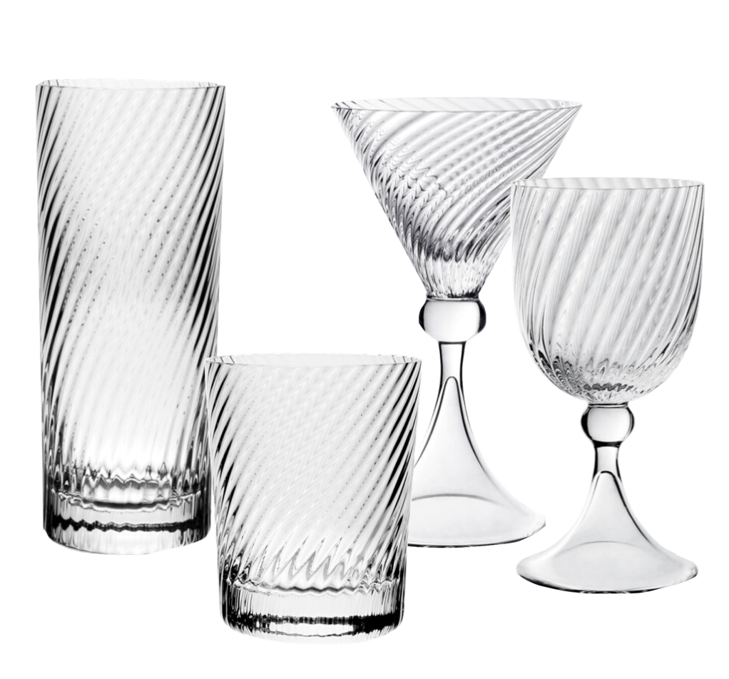 The Venetia Drinkware Collection by William Yeoward Crystal features four clear pieces—highball, lowball, martini glass with elegant stems, and goblet—with a diagonal swirl design inspired by Venetian artistry, displayed on a white background.