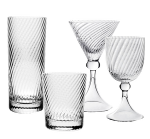 The Venetia Drinkware Collection by William Yeoward Crystal features four clear pieces—highball, lowball, martini glass with elegant stems, and goblet—with a diagonal swirl design inspired by Venetian artistry, displayed on a white background.