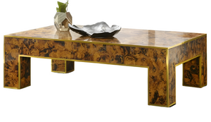 The Brice Cocktail Table by Modern History features a glossy marbled brown finish, brass edge detailing, and is styled with a plant-filled vase and a metal dish on top.