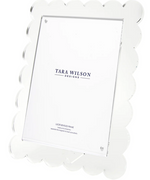 The Clear Scallop Frame, 8 x 10 by Tara Wilson Designs is an upright acrylic frame with scalloped edges, a lucite finish, and removable kickstand—an elegant wedding gift that comes with a branded insert.