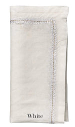 A folded white linen napkin from the Jardin Napkin Set by Kim Seybert, featuring visible edge stitching and "White" embroidered at the bottom.
