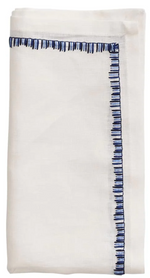 The Kim Seybert Filament Napkin Set features crisp white linen napkins, neatly folded with a blue embroidered border on two edges and elegant embroidered stitching.