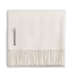 The Alicia Adams Alpaca Classic Throw Collection features a cream-colored baby alpaca blanket, fair-trade made in Peru, neatly folded with fringed edges and a small fabric label.