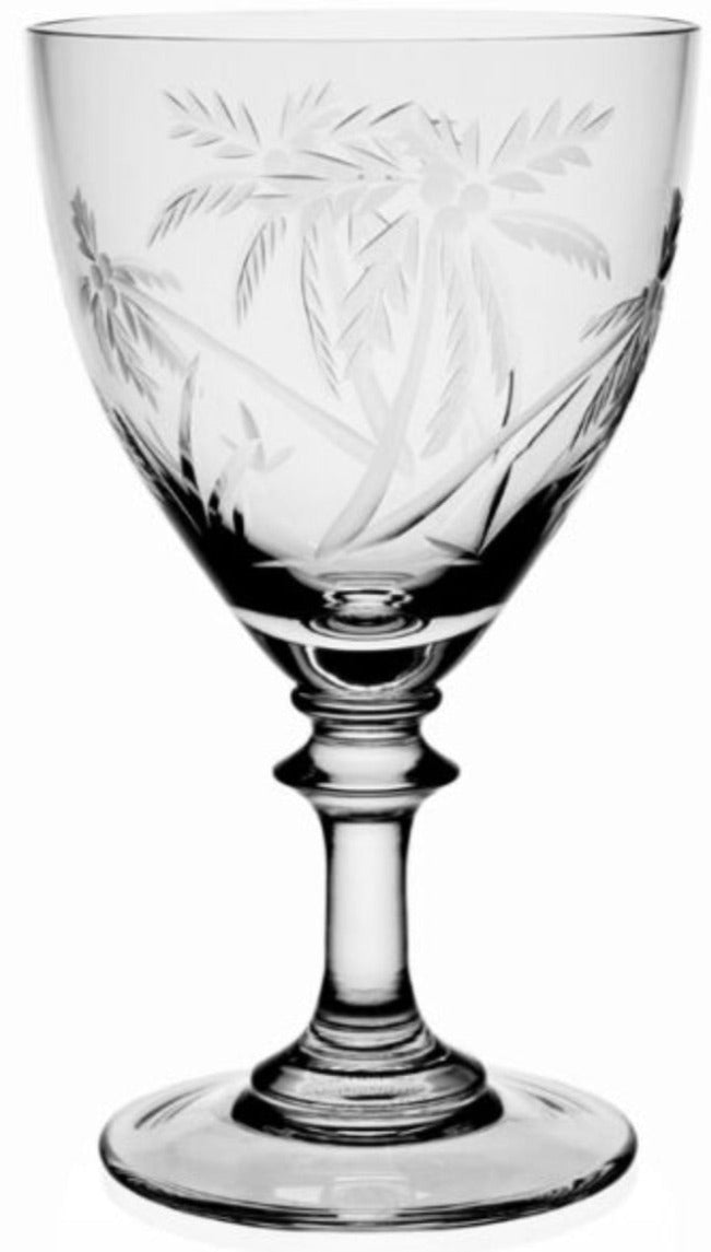 The Palmyra Drinkware Collection by William Yeoward Crystal features a clear etched glass goblet with a palm tree and landscape design, inspired by marine research around Palmyra Atoll, shown against a white background.