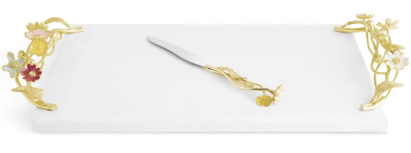 Elegant rectangular Michael Aram Wildflowers cheese board made of white marble, featuring intricate gold, botanical illustrations on the sides with a matching gold cheese knife.