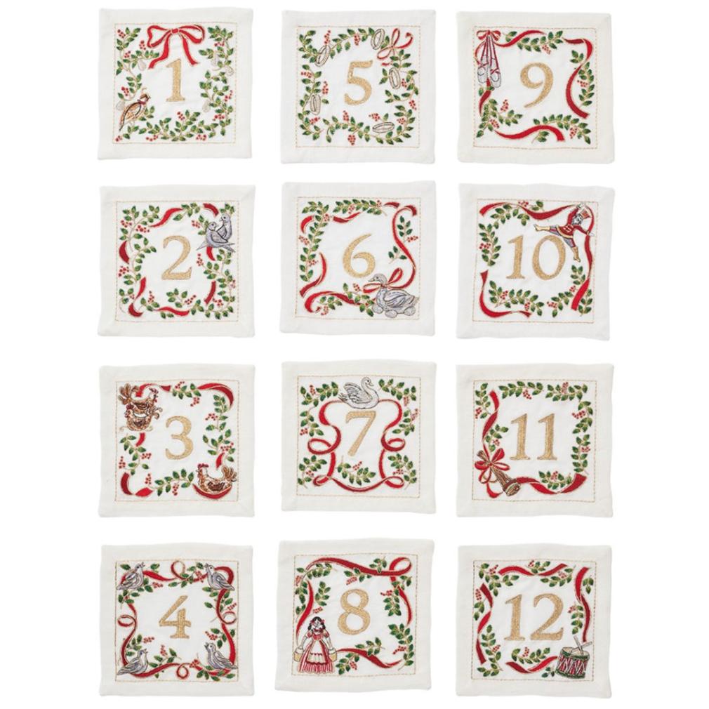 The Kim Seybert Christmas Carol Cocktail Napkins Set includes 12 embroidered fabric squares, each numbered 1–12 with festive holiday motifs and elegant borders—ideal for charming holiday gatherings.