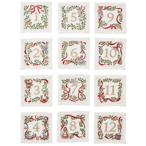 The Kim Seybert Christmas Carol Cocktail Napkins Set includes 12 embroidered fabric squares, each numbered 1–12 with festive holiday motifs and elegant borders—ideal for charming holiday gatherings.