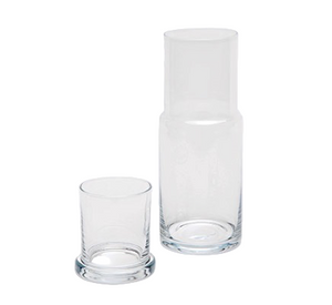 The Faro Clear Carafe by Pigeon & Poodle is placed beside an empty clear glass tumbler on a plain white background, embodying timeless hospitality.