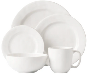 The Juliska Puro Whitewash Dinnerware Collection features two plates, a bowl, and a mug in classic white—ideal for serving teatime treats or savory tapas, elegantly displayed against a minimalist background.
