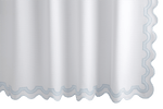 A Matouk Mirasol Shower Curtain, Blue, with a white diamond pique design, wavy scalloped edge, and light blue trim hangs vertically, combining elegance with the assurance of OEKO-TEX® certification.