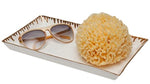 The Pigeon & Poodle Rio Gold and White Tray, a rectangular porcelain piece with metallic detail, holds sunglasses and a large natural sea sponge against a white background.