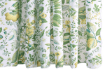 The Matouk Pomegranate Shower Curtain, Citrus displays green leaves and yellow flowers on a crisp white backdrop.