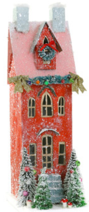 The Cody Foster Red Townhouse is a two-story decorative paper mache house, featuring snow, holiday wreaths, garlands, and small Christmas trees at the front.