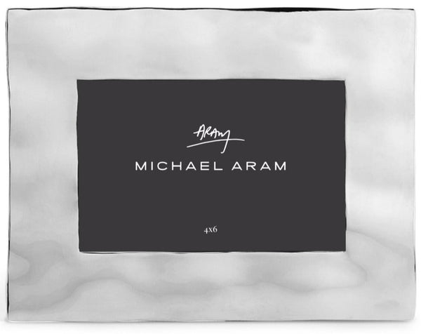 A Michael Aram branded Reflective Frame, 4 X 6 from the reflective collection, with a signature in the center, surrounded by a light border against a dark background.